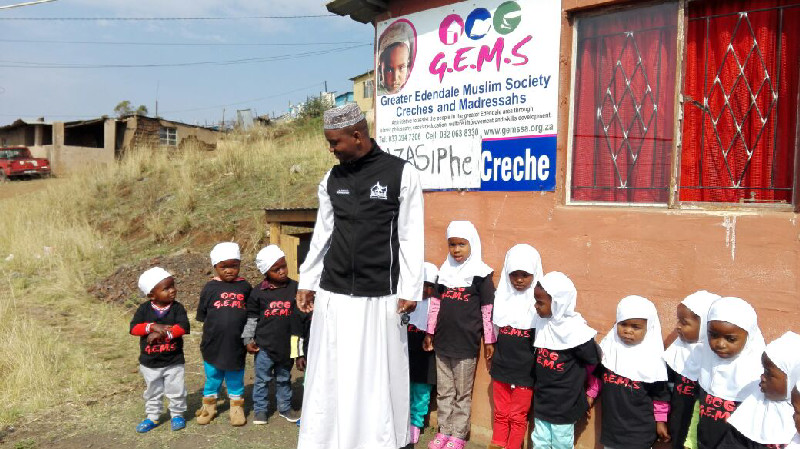 Young students at the Azasiphe Crèche take a moment to stand with Al-Imdaad Foundation’s MBP coordinator Ahmed Shazi
